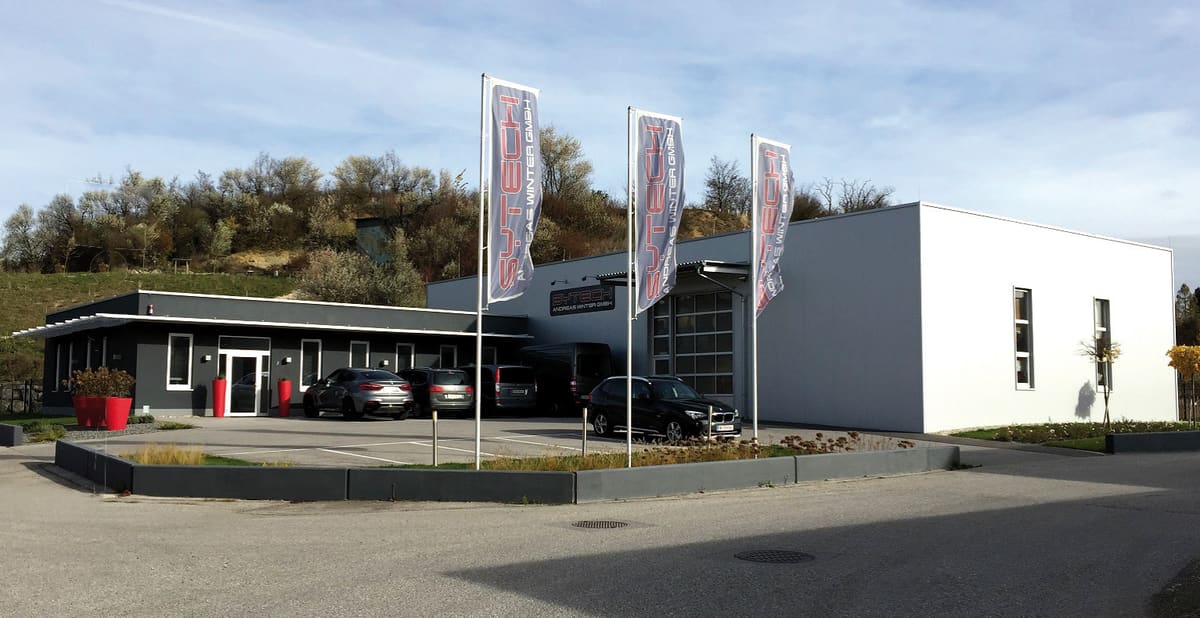 Firmengebäude der SYTECH Andreas Winter GmbH in Stetten mit Werbefahnen und Parkplatz
